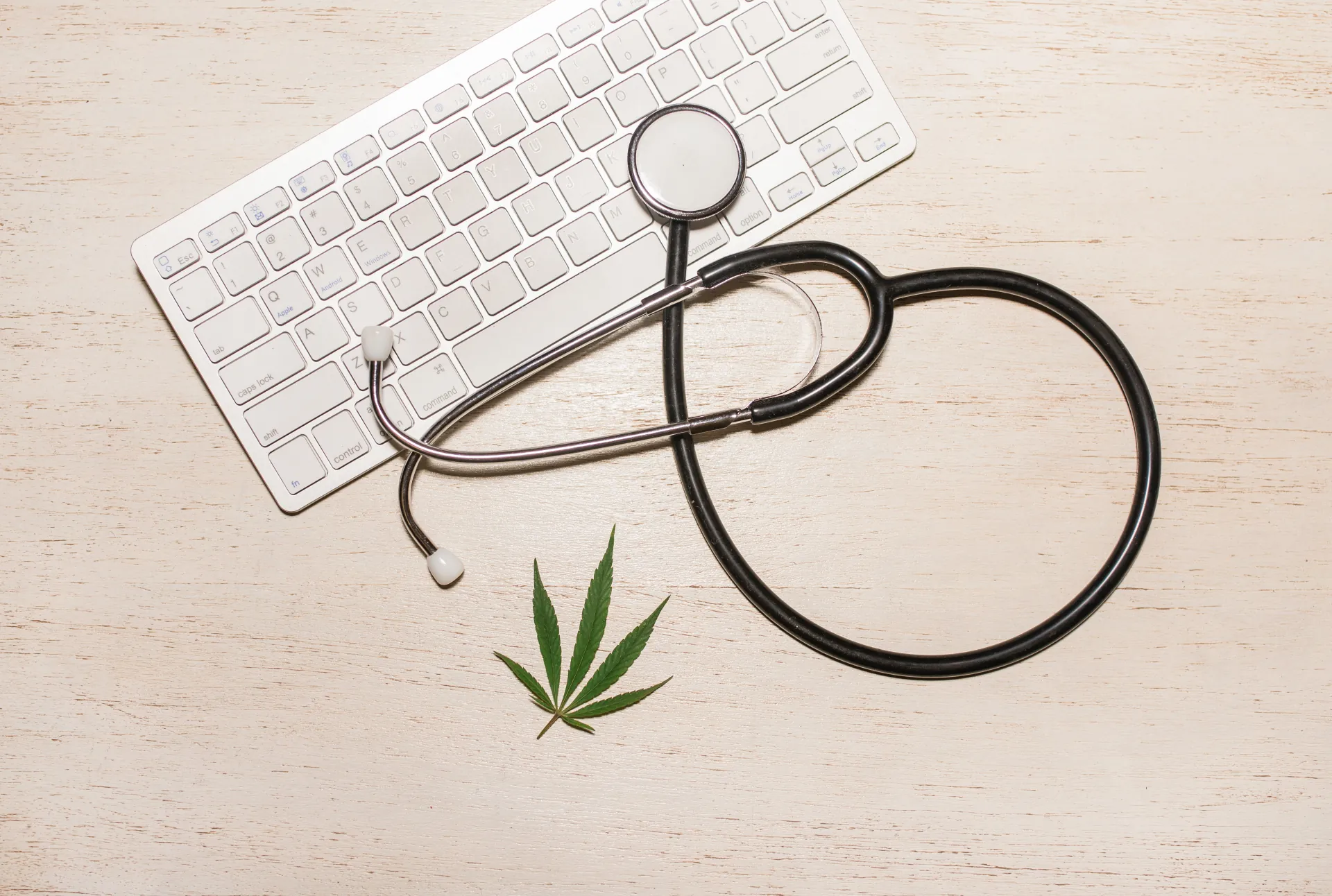 Stethoscope on cannabis leaf and keyboard